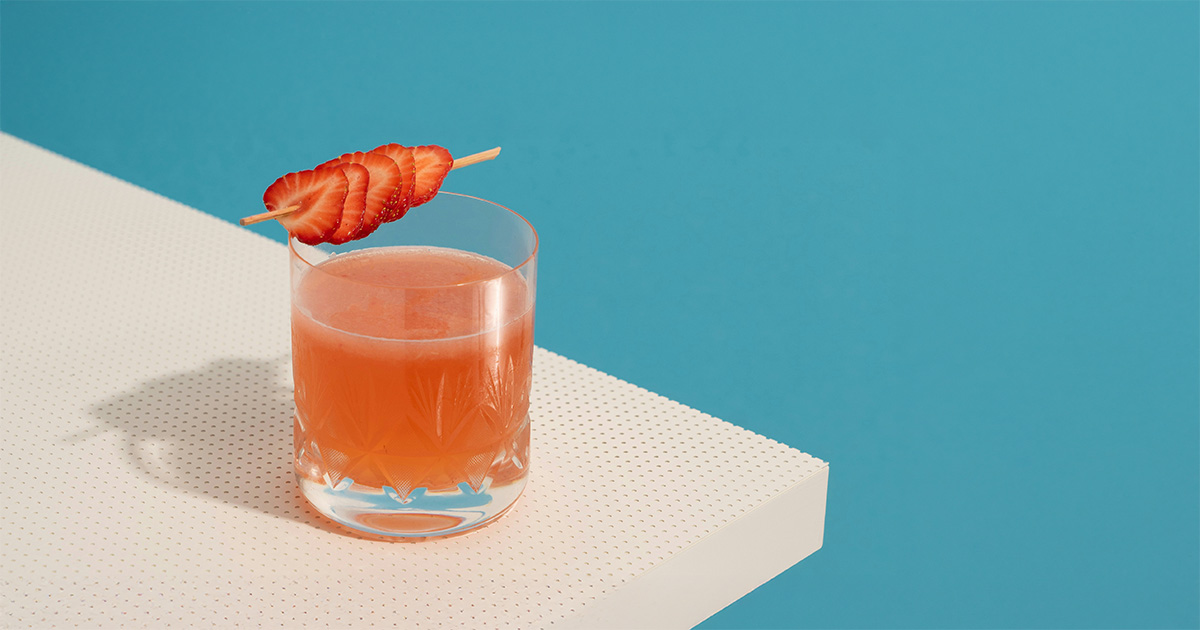A healthy beverage sitting on the countertop with strawberries on top